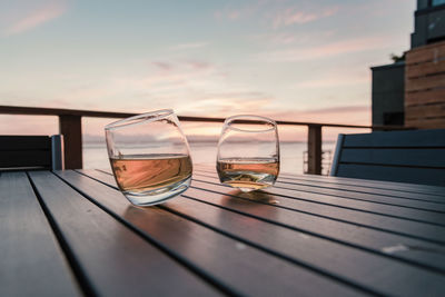 Close-up of whiskey in glasses on table during sunset