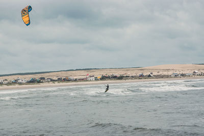 Man kite surfing in sea against sky