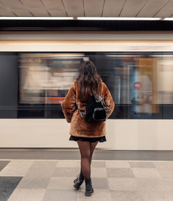 Rear view of young woman standing in subway