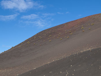 Scenic view of volcanic mountain against blue sky