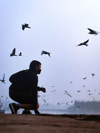 Low angle view of man flying against sky