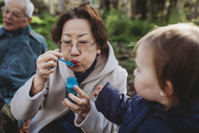 Close up portrait of grandmother blowing bubbles for granddaughter