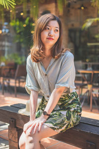 Portrait of young woman sitting on table