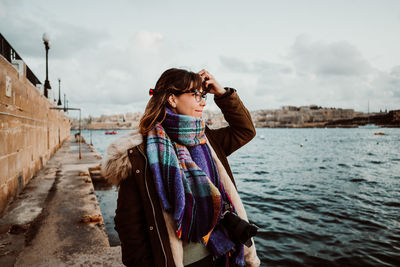 Woman standing by sea against sky