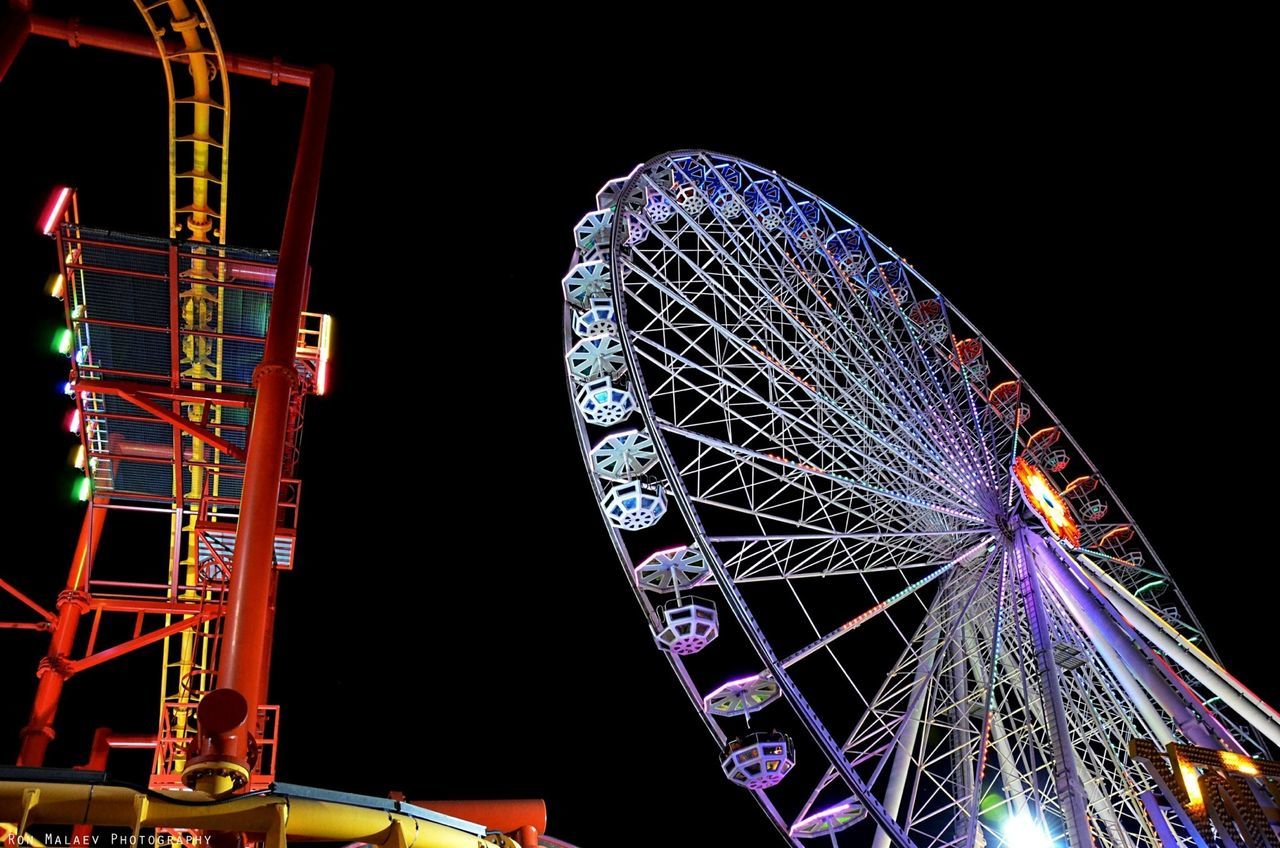 amusement park, amusement park ride, ferris wheel, arts culture and entertainment, night, illuminated, low angle view, built structure, architecture, sky, metal, clear sky, famous place, travel destinations, building exterior, fun, capital cities, city, traveling carnival, outdoors