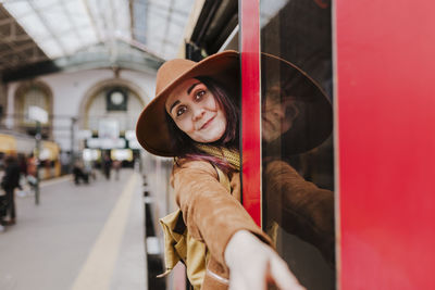 Portrait of smiling woman standing at entrance of train