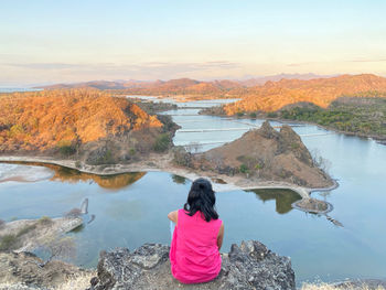 Rear view of woman looking at lake against sky