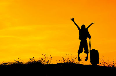 Silhouette of boy jumping with arms raised