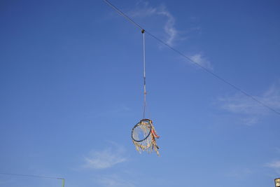 Low angle view of lighting equipment hanging against blue sky