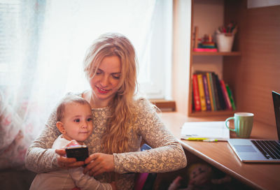 Portrait of smiling girl using mobile phone at home