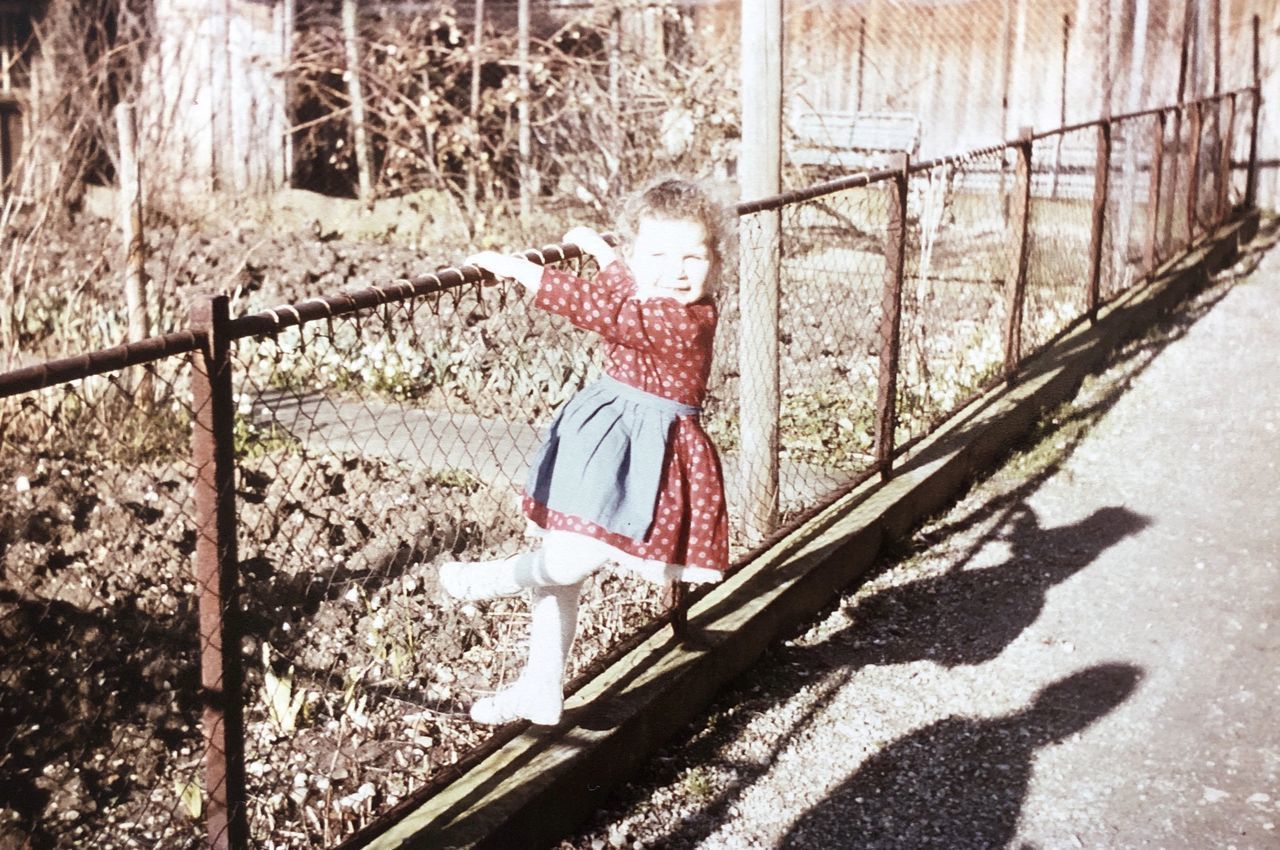 REAR VIEW OF WOMAN STANDING BY PLANTS ON WALKWAY