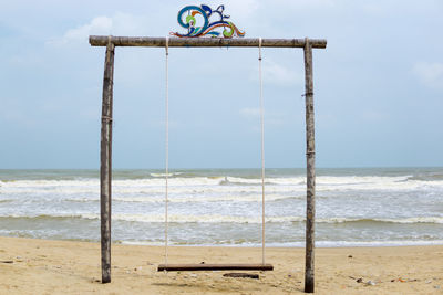 Lifeguard hanging on beach against sky