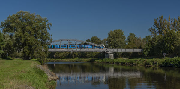 Arch bridge over river against blue sky