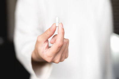 Woman's hand with a white medical pill close-up. health care, medical supplements concept