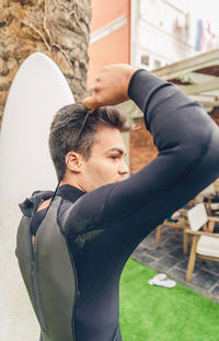 Young man wearing wetsuit on lawn