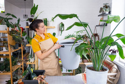 Portrait of smiling young woman holding potted plant