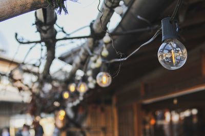 Low angle view of illuminated light bulb hanging from ceiling