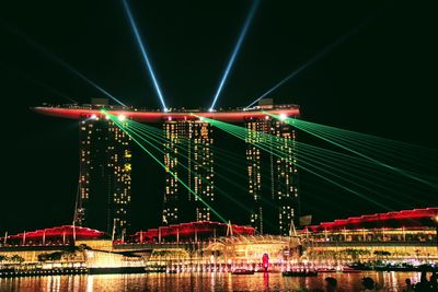 Illuminated bridge over river in city at night