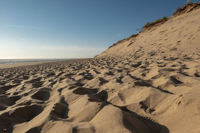 Scenic view of sand dune on beach against sky