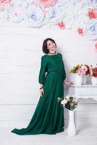 Portrait of woman standing by flowers at home