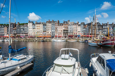 Boats moored in canal in city against sky