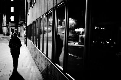 Rear view of man walking on illuminated street at night