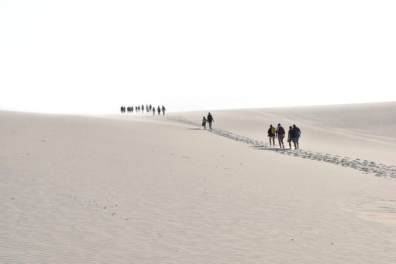 PEOPLE WALKING ON SAND DUNE AT BEACH