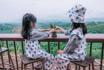 A beautiful asian girl sitting on balcony and looking at mountains and green