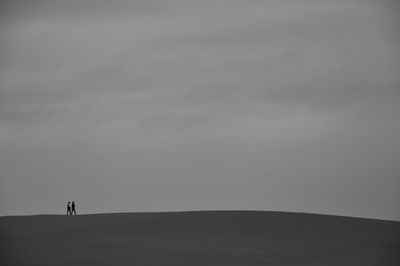 Silhouette people walking on landscape against the sky