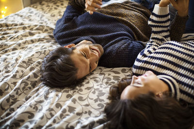 High angle view of happy couple lying on alcove window seat at home