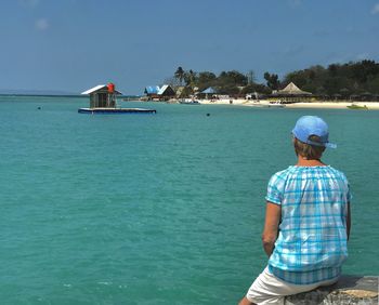 Rear view of man standing on sea against sky