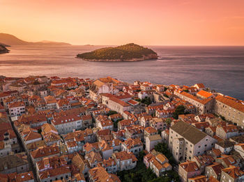 High angle view of townscape by sea against sky during sunset