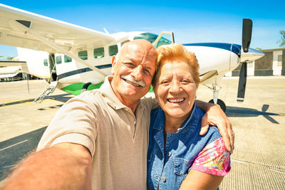 Portrait of smiling senior couple against airplane