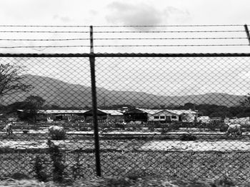 Fence on field by building against sky