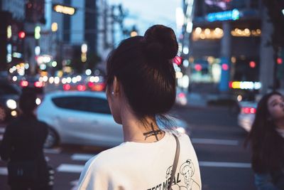 Rear view of woman on illuminated street at night