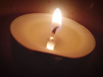 Close-up of lit candle in darkroom