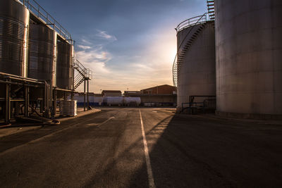 Road by factory against sky