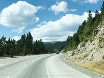 Empty road amidst trees against sky