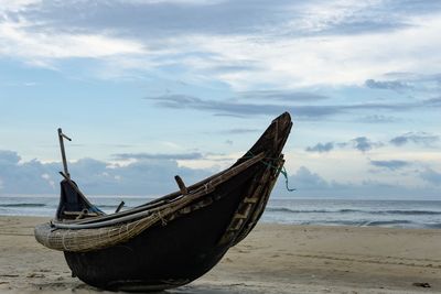 Boat moored on beach against sky