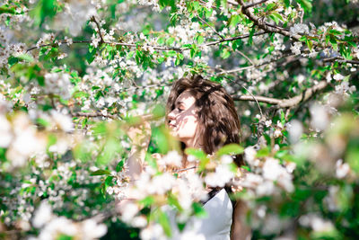 Portrait of young woman with flower petals on tree