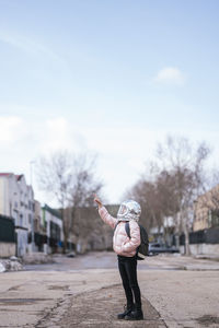 Girl wearing space helmet pointing at sky while standing on road