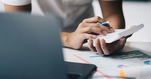 Midsection of man using mobile phone on table