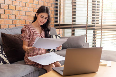 Full length of woman sitting on laptop