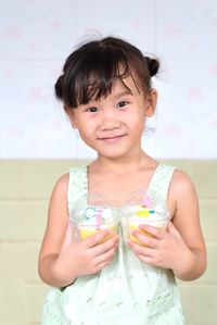 Portrait of cute smiling girl holding indoors