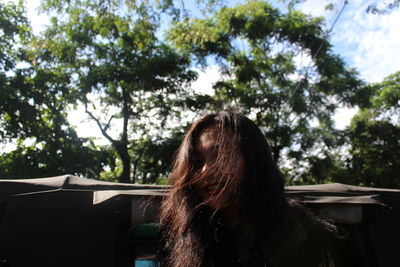 Woman with messy hair against trees