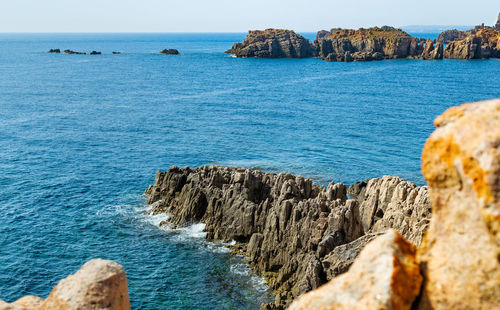 Rocks on sea shore against blue sky