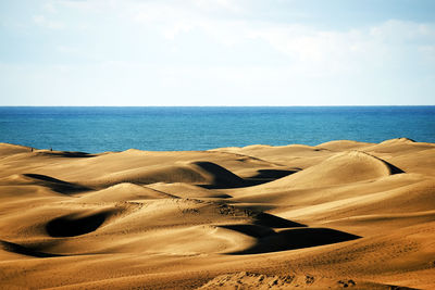 Scenic view of desert and sea against sky