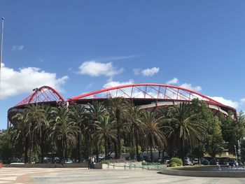 Ferris wheel by palm trees against blue sky