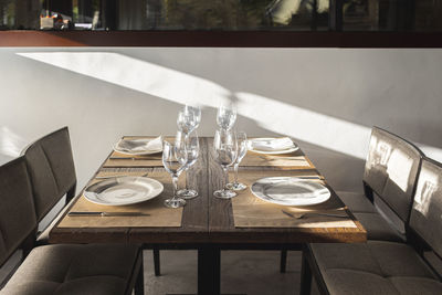 Wineglasses and plates arranged on table in restaurant