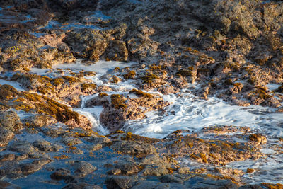 Water of the pacific ocean running across rocks back into a blowhole